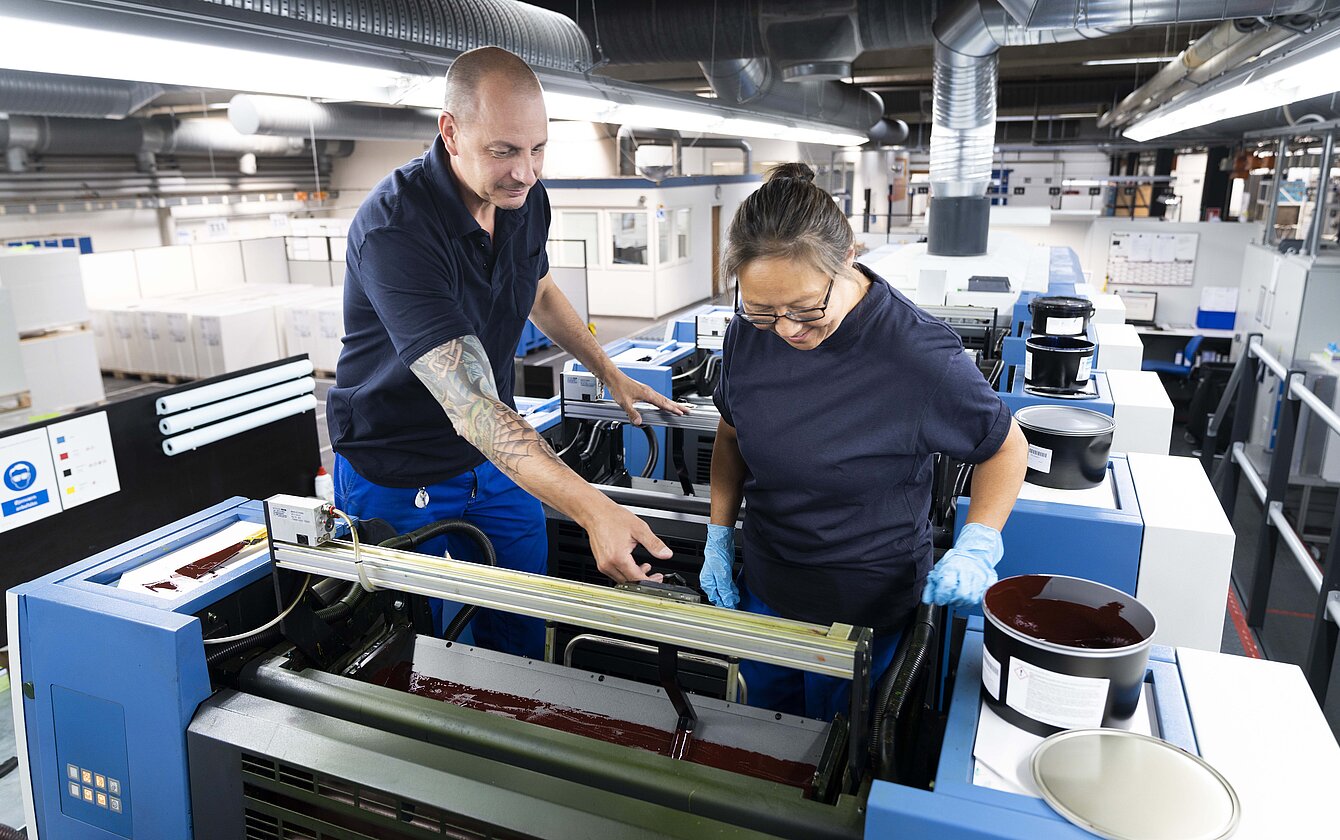 Mitarbeiter arbeiten gemeinsam an Druckmaschine
