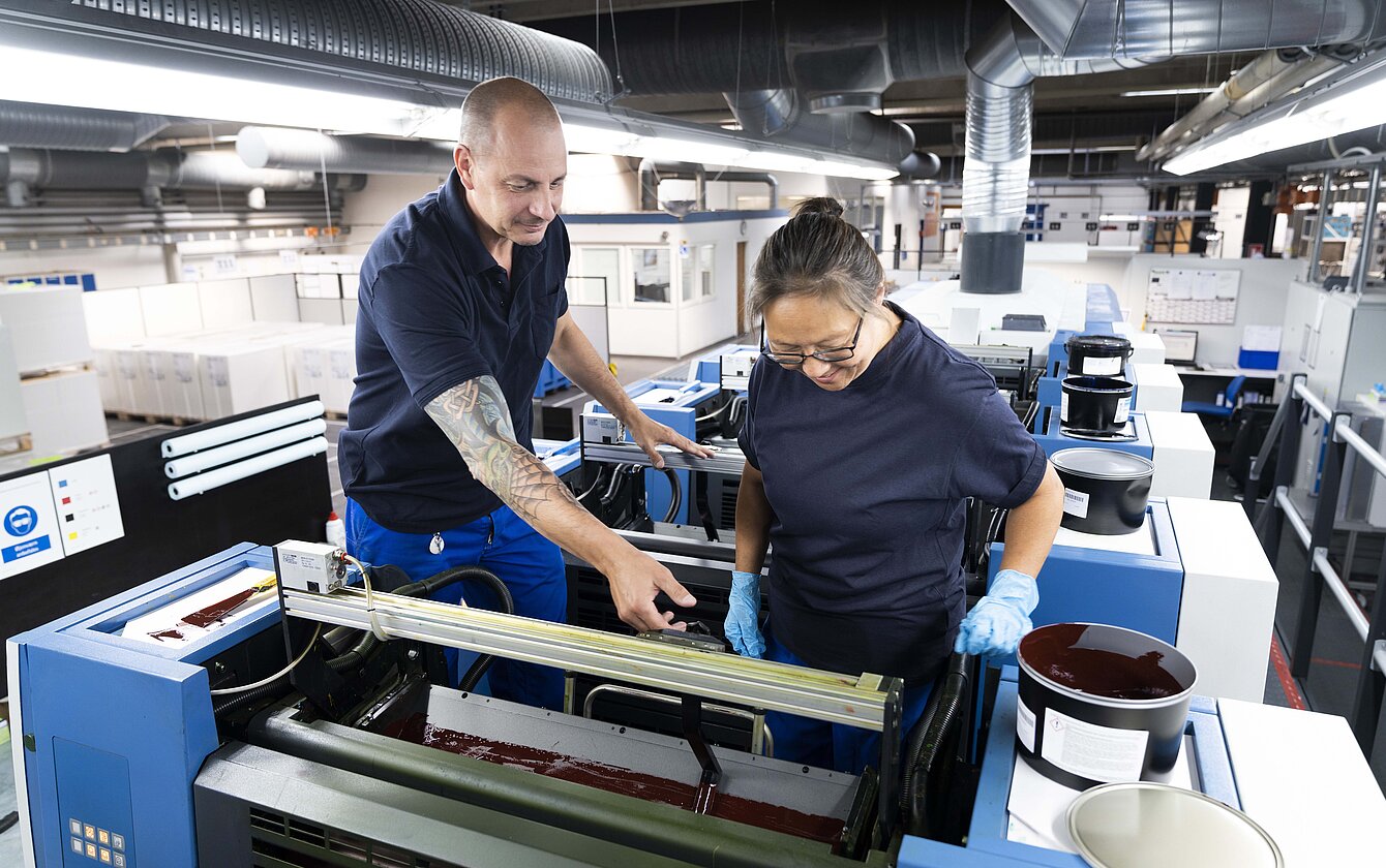 Mitarbeiter arbeiten gemeinsam an Druckmaschine