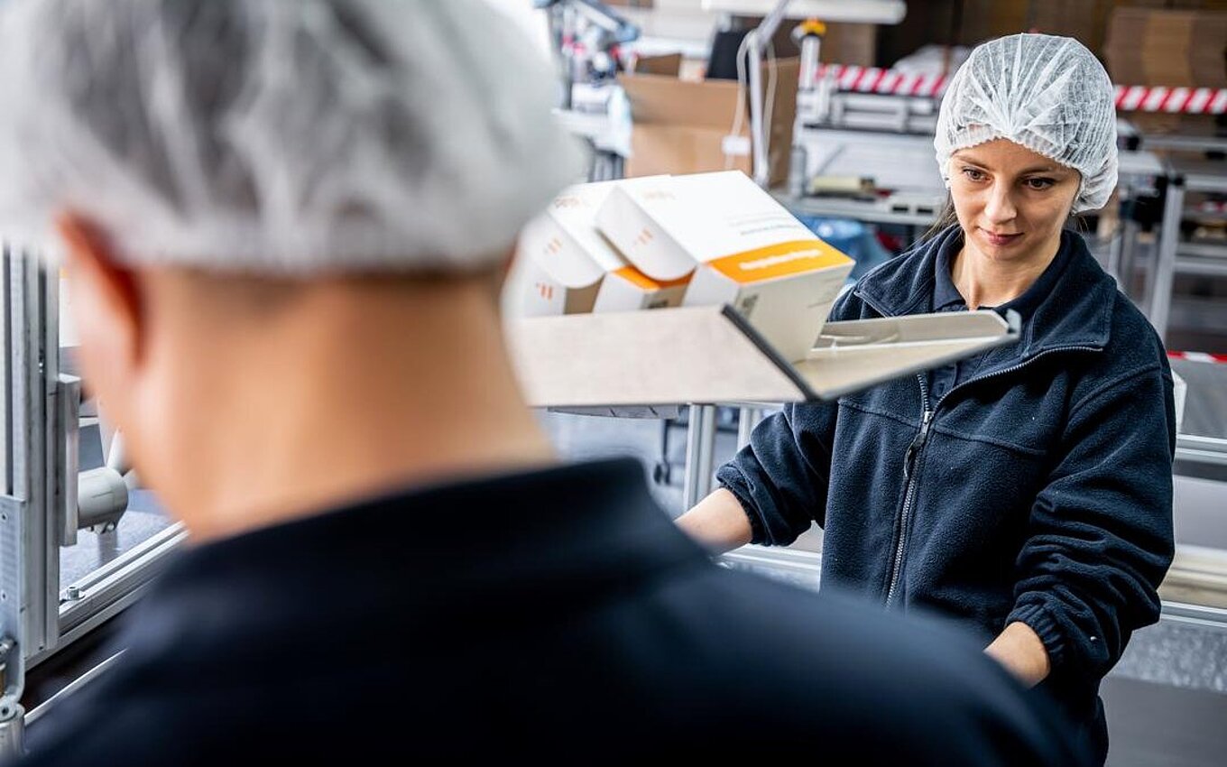 An efficient packaging line at Faller Packaging – an employee monitors pre-assembled folding boxes in the PrePackaging Service.