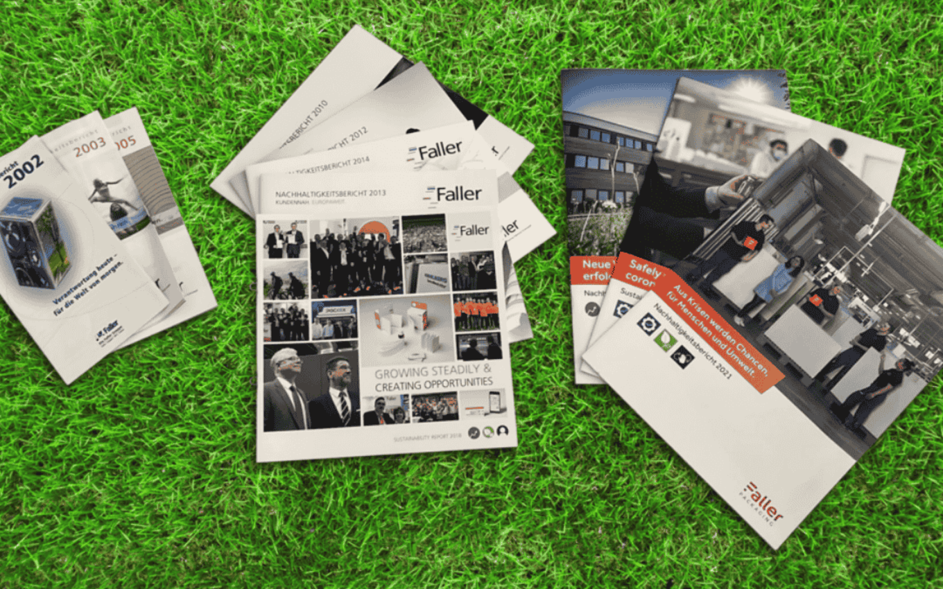 [Translate to English:] Mehrere Nachhaltigkeits- und Geschäftsberichte von Faller Packaging liegen auf einer grünen Wiese. Die Titel zeigen die Entwicklung des Unternehmens über die Jahre hinweg – von frühen Berichten bis zu aktuellen Ausgaben mit Fokus auf Nachhaltigkeit, Wachstum und Zusammenarbeit.