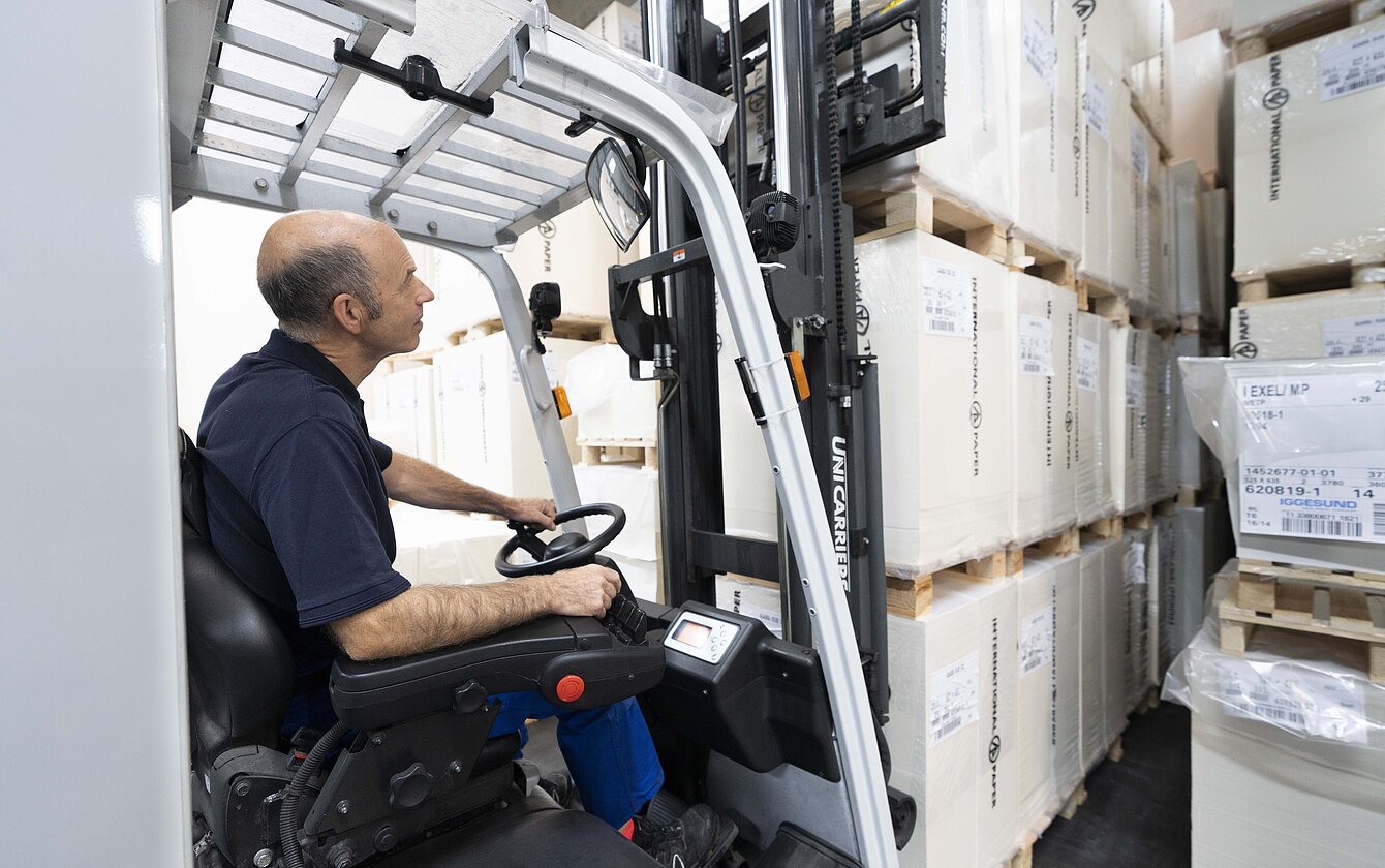 Logistikmedarbejder på lageret opbevarer paller med gaffeltruck